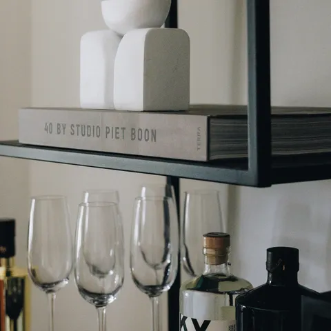 Sfeervolle kantoorstyling van LG Vastgoed met decoratieve objecten, glazen en flessen op een moderne kast