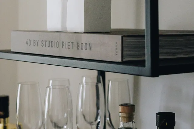 Sfeervolle kantoorstyling van LG Vastgoed met decoratieve objecten, glazen en flessen op een moderne kast