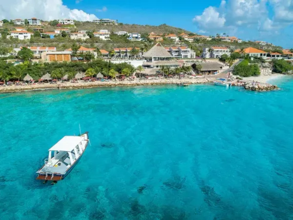 een blauwe zee met een boot op curacao coral estate
