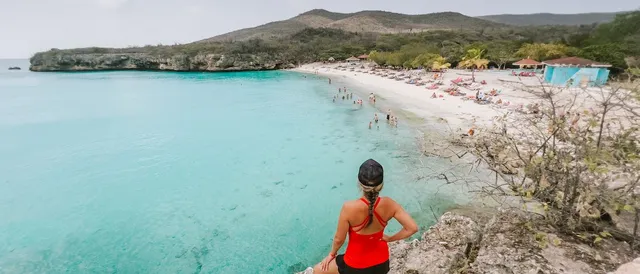 westpunt grote knip strand en een vrouw die op de klip staat