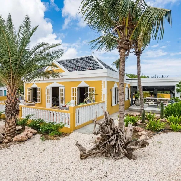 Geel landhuis met veranda en palmbomen — Landhuis Mishé, Curaçao.