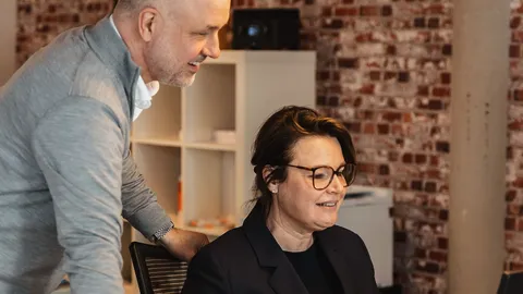 Makelaar overlegt met een collega aan haar bureau op kantoor