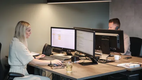 Medewerker aan het werk achter twee beeldschermen op kantoor