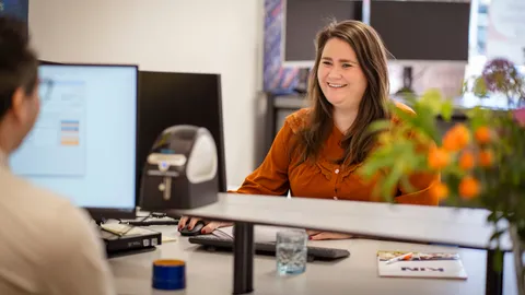 Lachende medewerker aan de balie van het KIN-kantoor