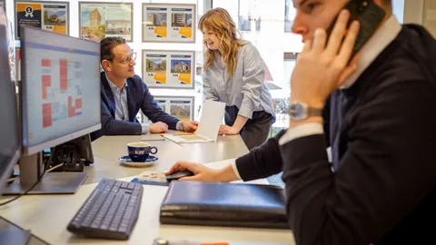 Medewerkers aan het werk in het kantoor met woningaanbod aan de muur