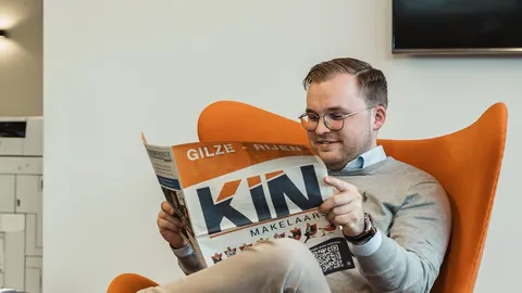 Medewerker leest het KIN-magazine in een oranje stoel
