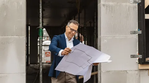 Makelaar bekijkt een bouwtekening op een bouwplaats