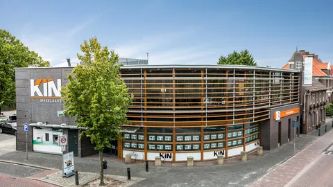 Rond kantoorpand met KIN-logo's aan een straathoek